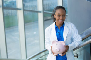 A trainee dental nurse holding a piggy bank