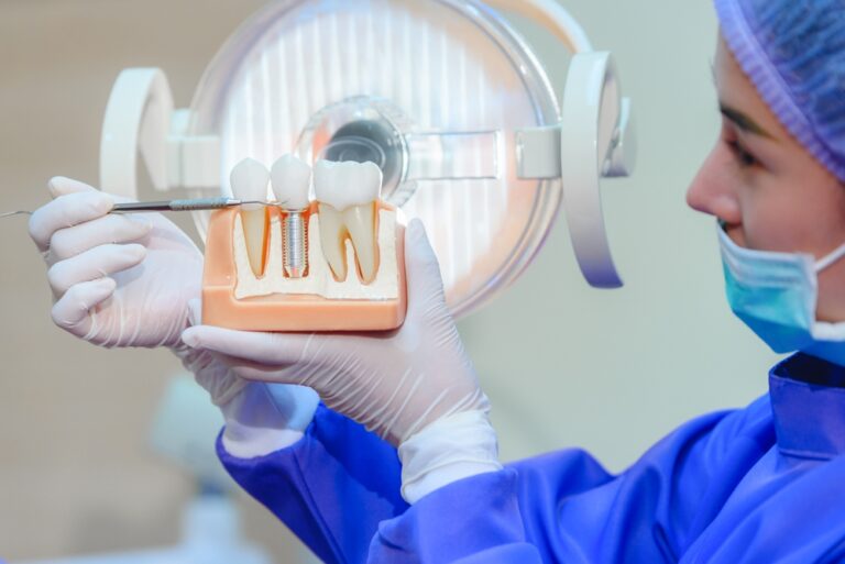 a dental nurse showing a teeth model and pointing to the crown of a dental implant.
